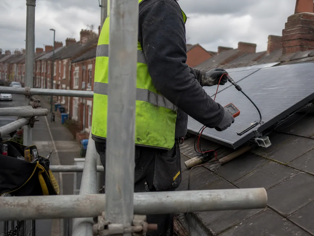 Engineer testing the cable connectors under a solar panel on a Birmingham terrace roof