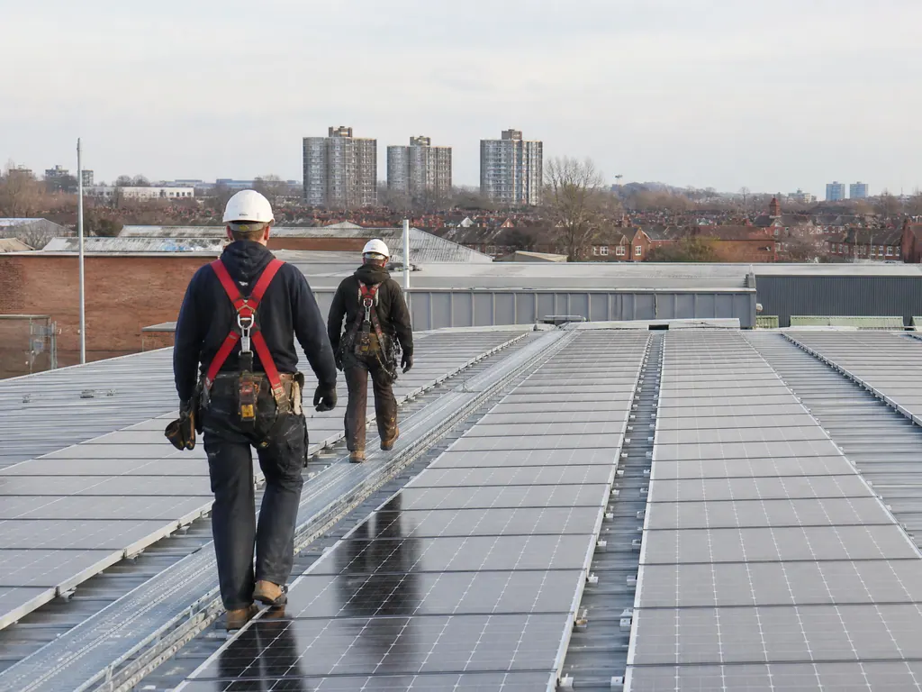 Installers walking between rows of solar panels on a warehouse roof in the West Midlands