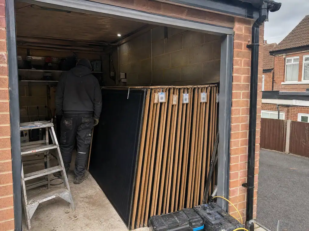 Solar panels labelled and stored in a garage during roof work, Birmingham